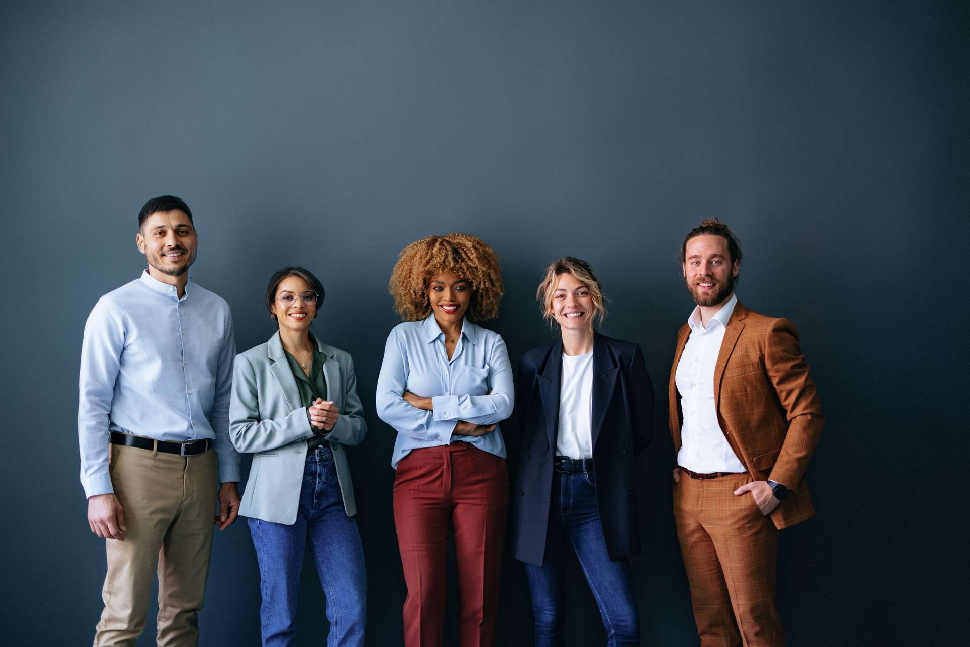 Portrait Of Smiling Businesspeople Standing In Front Of Black Wall